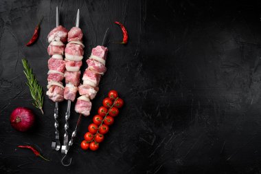 Şiş seti üzerinde bir barbekü salamurasında et, üst görünüm düz, metin için kopya alanı, siyah koyu taş masa arka planında