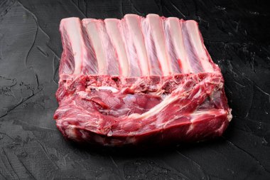 Kuzu pirzolası, kemikli çiğ et, siyah taş masa arkaplanı, metin için kopyalama alanı
