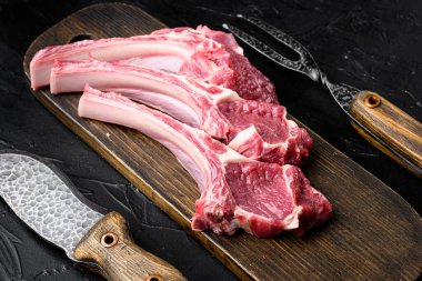 Çiğ kuzu pirzola biftek seti, siyah taş masa arka planında.