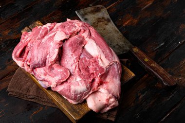 Çiğ kuzu omuz eti pişirme seti için hazır, eski, siyah ahşap masa arkasında.