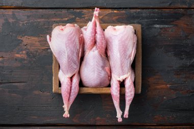 Taze organik bıldırcın eti, düz, koyu ahşap arka planda.