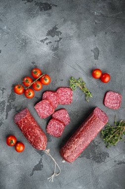 Taze biberiye ve baharatlarla salam, gri taş masa arkaplanı, üst görünüm düz, metin alanı için kopya alanı ile