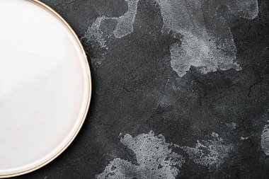 Metin veya yiyecek için kopyalama alanı olan boş seramik tabak seti, üst görünüm düz, siyah taş masa arkaplanı üzerinde