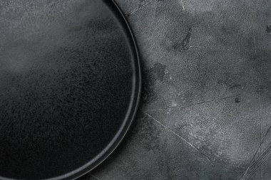 Gri taş masa arkaplanındaki siyah plaka kümesinin üst görünümü