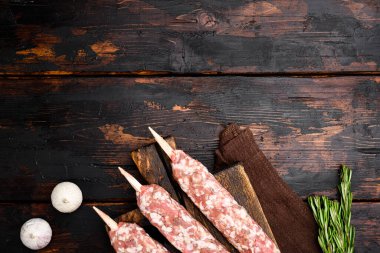 Çiğ lula kebabı, liulya-kebap kıymalı et, şiş kebap pişirmeye hazır, eski, siyah ahşap masa zemininde, üst görünüm düz, metin için kopya alanı ile