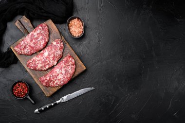 Çiğ biftek köftesi seti, siyah koyu taş masa arkaplanı, üst görünüm düz yatay, metin için kopyalama alanı ile