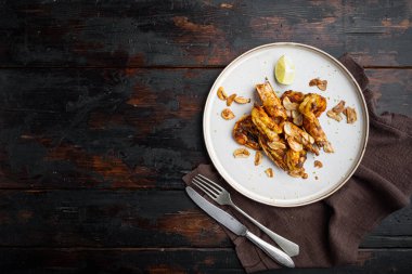 Izgara kırmızı Arjantin karidesleri tabakta, eski siyah ahşap masa zemininde, telif alanı ve metin için yeri olan düz manzaralı, deniz ürünleri seti pişiriyorlar.