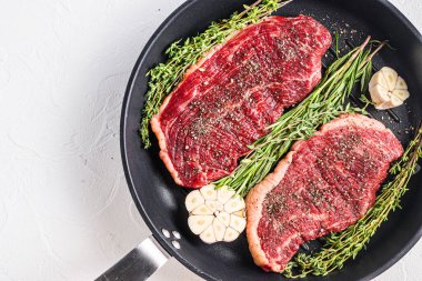 İki çiğ Picanha organik bifteği tavada ızgara ve sarımsak ile hazır. Beyaz desenli arkaplan üzerinde, metin için boşluk olan üst görünüm