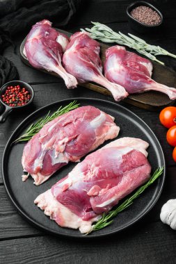 Otlar ve malzemelerle birlikte, siyah ahşap masa arkasında ördek eti.