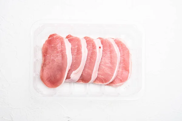 Zestaw Surowego Mięsa Wieprzowego Plasterkach Plastikowym Opakowaniu Białym Kamiennym Tle — Zdjęcie stockowe