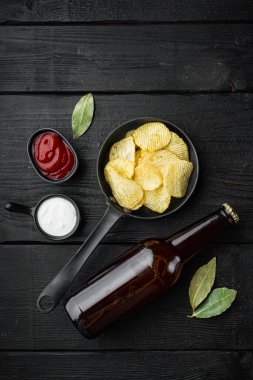 Çıtır patates cipsi seti, ve siyah ahşap arka planda bir şişe bira, en üstteki düz zemin, metin için fotokopi alanı ile