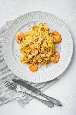 Pesto karidesli makarna servis edilir, tabakta, beyaz taş yüzeyde, üst manzara düz yatar.