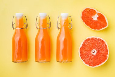 Meyve suyu setiyle olgunlaşmış greyfurt, sarı desenli yaz arka planında, üst manzara düz.