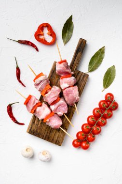 Kebaplar şiş sette çiğ et ve sebzeler, üst manzara düz, beyaz taş masa zemininde