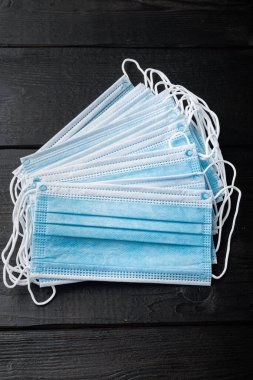 Tıbbi koruyucu tek kullanımlık maske, cerrahi maske, koronavirüs karantinası, hijyen konsepti, siyah ahşap masa manzarası.