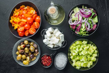 Yunan salatasının ana malzemeleri: Taze zeytin karışımı, feta peyniri, domates biberi, siyah arka planda, üst görünüm düz.