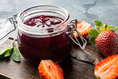 Doğal çilek reçeli kavanozu, gri arka planda.