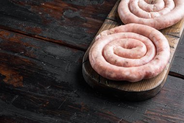 Çiğ spiral sosis seti, eski koyu ahşap masa zemininde, metin kopyalanması için alanı var.