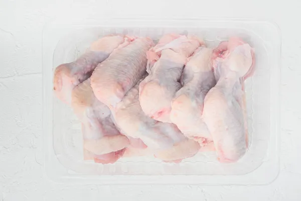 Surowe Skrzydełka Kurczaka Plastikowym Opakowaniu Białym Kamiennym Tle Widok Góry — Zdjęcie stockowe