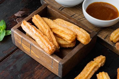 Churros 'a toz şeker serpiştirilmiş, eski, siyah ahşap masa arkaplanı üzerine.