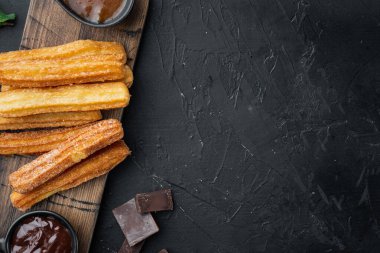 Churros pudra şekeri serpiştirilmiş, siyah arkaplan üzerine, üst görünüm düz metin, kopyalanma alanı ile yatıyordu