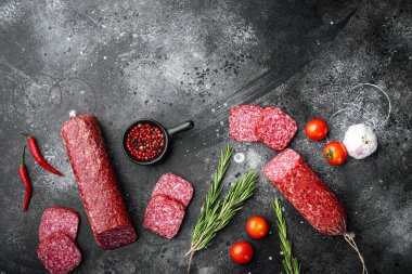 Bitki ve baharatlı salam, siyah taş masa arkaplanı üzerinde, üst görünüm düz, metin alanı için kopyalama alanı ile