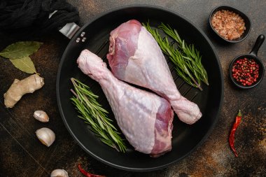 Hindi eti, baharatlı çiğ but, kızartma demir tavada, eski koyu kırsal masa zemininde, üst manzara düz