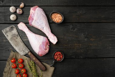 Çiğ organik hindi bacakları, yemek pişirme seti için malzemeler, eski kasap bıçağı, siyah ahşap masa arkaplanı, üst görünüm düz, metin için kopyalama alanı