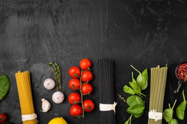 Üç renk kuru hamur makarna seti, siyah koyu taş masa arkaplanı, üst görünüm düz yatay, metin için kopyalama alanı