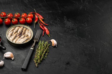 Siyah taştan masa arkaplanının üzerinde tütsülenmiş balık konservesi ve metin için kopya alanı var.