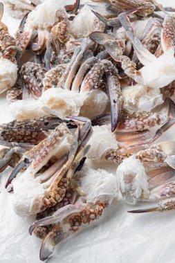 Donmuş mavi yüzen yengeç parçaları beyaz arkaplanda.