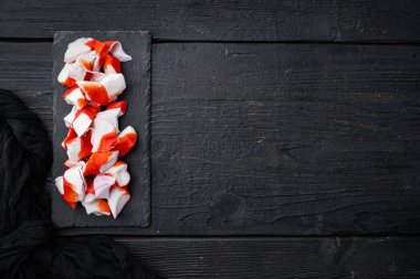 Taze Yengeç eti çubuğu surimi seti, siyah ahşap masa arkaplanı üzerinde, telif alanı ve metin alanı ile üst görünüm düz yatar