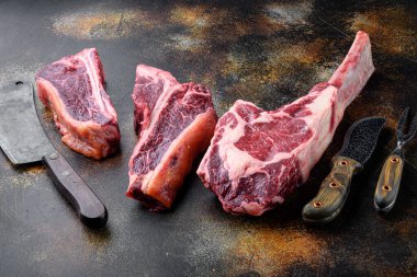Etin çeşitli kesimleri kurumuş sığır eti seti, tomahawk, et kemiği ya da biftek, eski kasap bıçağı ile eski siyah rustik arka plan