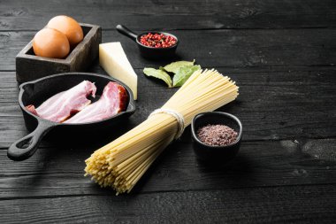Carbonara geleneksel İtalyan makarna seti için taze ham malzemeler, siyah ahşap zemin üzerinde, metin için kopya alanı ile