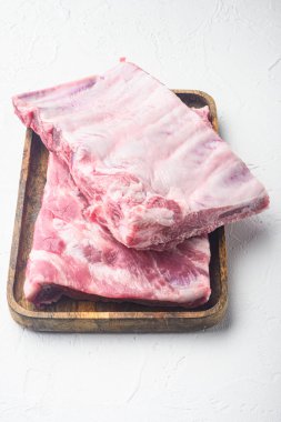 Taze çiğ domuz pirzolası, ahşap servis tahtasının üzerinde, beyaz taş arka planda.