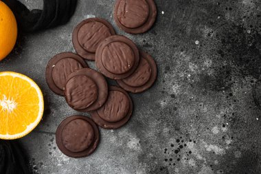 Jaffa Kekleri. Kurabiyeler koyu çikolatayla kaplı ve içi turuncu marmelat setiyle dolu, siyah siyah taş masa zemininde, üst görünümü düz, metin alanı için fotokopi alanı var.