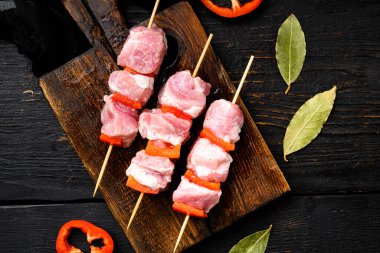 Kebaplar şiş sette çiğ et ve sebzeler, üst manzara düz yerde, siyah ahşap masa arka planında.