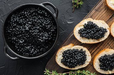 Siyah mersin balığı havyarlı kanepe, siyah arka planda, üst manzara düz.