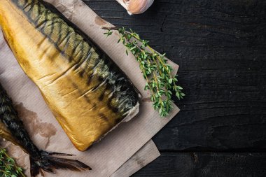 Tütsülenmiş balık uskumrusu, siyah ahşap masa arkaplanı, üst görünüm düz metin alanı için fotokopi alanı ile yatıyordu