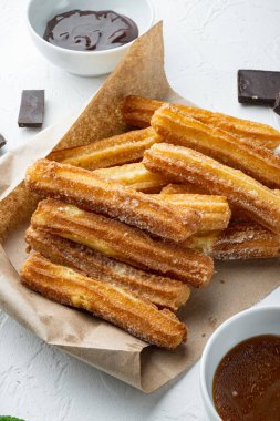 Tipik İspanyol çerez churros, kızarmış hamur pastası genellikle çikolatalı, acı sos setiyle servis edilir, beyaz arka planda.