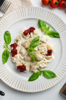 Domates soslu ravioli, peynir ve fesleğen, fesleğen, parmesan ve beyaz tabakta domates.