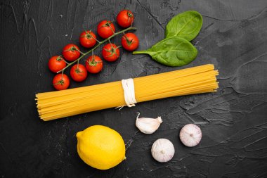 Spaghetti çiğ kuru malzemeler seti, siyah taş masa arkaplanı üzerine, üst görünüm düz yatıyordu