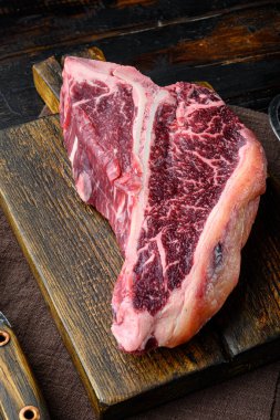 Biftek ya da ızgara ya da barbekü seti için biftek, ahşap kesim tahtasına, eski, siyah tahta masa arkasına.