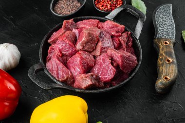 Tatlı dolma biberli taze kesilmiş sığır eti, dökme demir tavada, siyah taş arka planda.