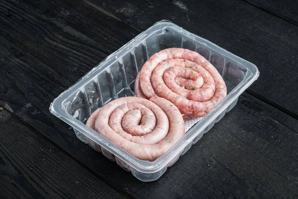 Raw Spiral Sausage Set Black Wooden Table Background Plastic Pack — Stock Photo, Image