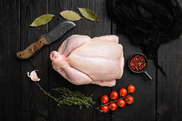 Organic raw whole chicken set, on black wooden table background, top view flat lay