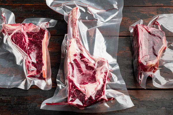 Dry aged vacuum steak  set, tomahawk, t bone and club steak cuts, on old dark  wooden table background