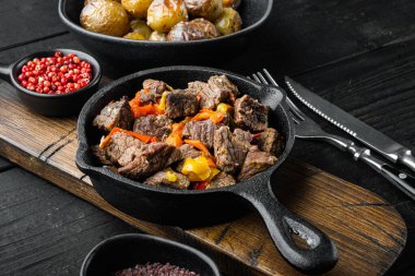 Tatlı dolma biberli et güveci ve defne yaprağı seti, dökme demir tavada, siyah ahşap arka planda.