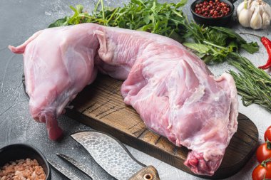 Çiğ ve taze et. Tüm tavşan, gri taş arka planda malzemelerle pişirmeye hazır.