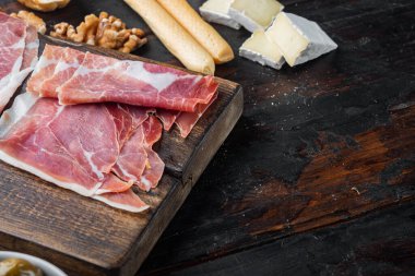 Dilimlenmiş jamon seti, koyu ahşap arkaplan ve metin için kopyalama alanı